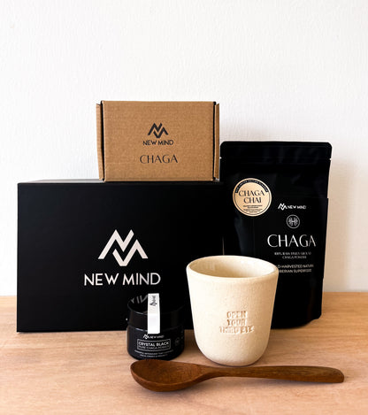 NEW MIND Chaga Energy Gift Box bundle including a Chaga tea bag, Chaga extract jar, ceramic cup, wooden spoon, and gift boxes.